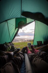 two people in a tent looking out to sea